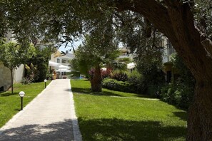 A pathway leading to a building with a covered outdoor seating area. - Renaissance Hanioti Resort (Kassandra)