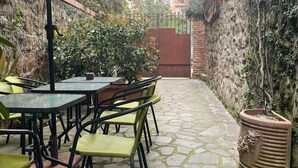 An outdoor patio with stone flooring, green and yellow chairs, and a table under a large umbrella. - Città Giardino B&B - Un'oasi di tranquillità vicino la metro Conca d'Oro (Roma)