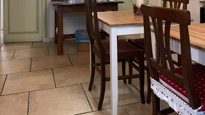 A dining area with a wooden table and chairs, a wall-mounted light fixture, and framed pictures. - Città Giardino B&B - Un'oasi di tranquillità vicino la metro Conca d'Oro (Roma)