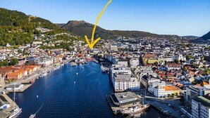 A coastal cityscape with a prominent river, historic buildings, and a mountainous backdrop. - Homey house in the heart of Bergen on a quiet street (Vestland)