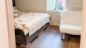 A bedroom with a bed, a chair, a window, and a ceiling light. - Homey house in the heart of Bergen on a quiet street (Vestland)