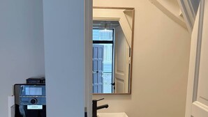 A small bathroom with a white sink, a mirror, and a toilet. There is a window above the sink and a door leading to another room. - Homey house in the heart of Bergen on a quiet street (Vestland)