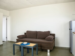 A compact living space with a brown sofa, a small table with a bowl, and a white refrigerator. - Romantic 1BR with Ocean View, Salt Pans with Flamingos and Infinity Pool (Curacao)