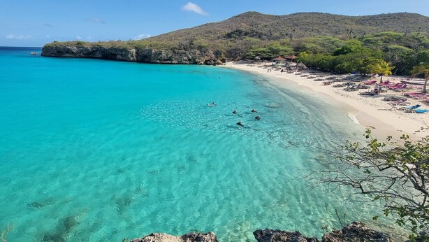 A coastal beach with clear turquoise water, a sandy shore, and a rocky outcrop. - Romantic 1BR with Ocean View, Salt Pans with Flamingos and Infinity Pool (Curacao)