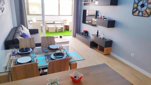 Una sala moderna con comedor, un sofá, un televisor y un reloj en la pared.