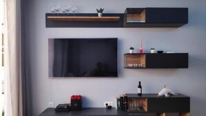Una sala de estar moderna con un televisor de pantalla plana grande, estanterías empotradas, una mesa de centro y una mesita auxiliar.