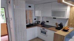 Una cocina moderna con armarios blancos, encimera de madera, horno integrado y frutero.