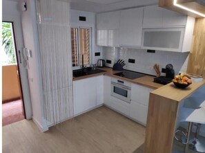 Eine moderne Küche mit weißen Schränken, einer Holzarbeitsplatte, einem eingebauten Backofen und einer Obstschale.