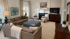 A spacious living room with a sectional sofa, a fireplace, a television, and a dining area. - Upscale 5BR House in Morningside – Perfect for World Cup Groups (Atlanta)