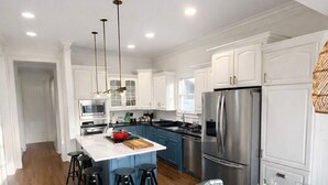 A modern kitchen with white cabinets, stainless steel appliances, and a central island with stools. - Upscale 5BR House in Morningside – Perfect for World Cup Groups (Atlanta)