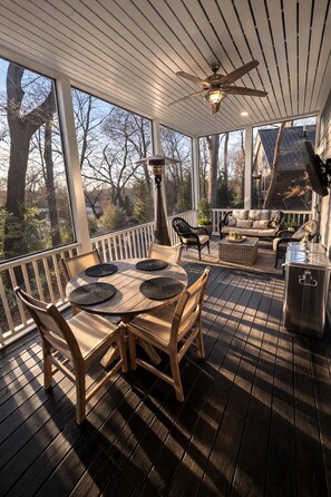 A covered outdoor deck with a wooden table and chairs, a ceiling fan, and a grill. - Upscale 5BR House in Morningside – Perfect for World Cup Groups (Atlanta)