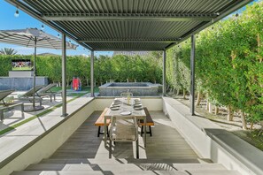 Eine Terrasse im Freien mit Esstisch, Stühlen und einem Whirlpool.