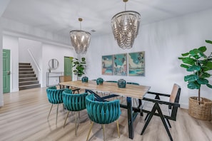 Ein Essbereich mit einem Holztisch, stuhlartigen Sitzgelegenheiten in Türkis und einer Pendelleuchte.