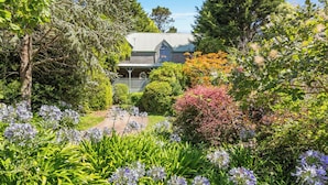 Une maison entourée d’une végétation luxuriante et de plantes en fleurs.