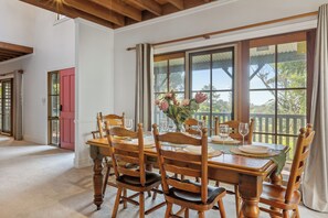 A dining room with a wooden table set for four, surrounded by wooden chairs.