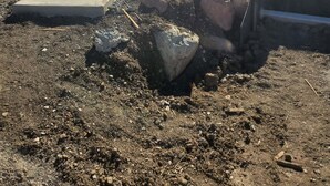 Eine Baustelle mit einem Betonweg, der zu einem Gebäude mit überdachtem Bereich führt.