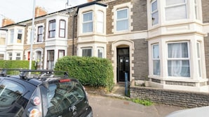 A row of terraced houses with a black car parked in front.