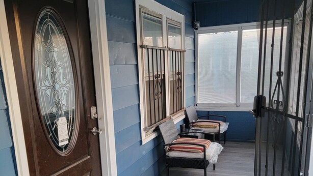 A porch with a door, a bench, a chair, and a screen door. - Spacious 2-bedroom house in enchanting Kansas City with AC, NSD-STRMAJ-00254  (Kansas City)