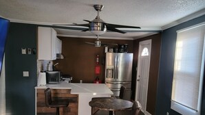 A modern kitchen with a central island, bar stools, and a ceiling fan. - Spacious 2-bedroom house in enchanting Kansas City with AC, NSD-STRMAJ-00254  (Kansas City)