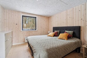 A bedroom with a bed, a window, wooden walls, and a ceiling. - Holiday home near beach and Limfjord (Thyholm)