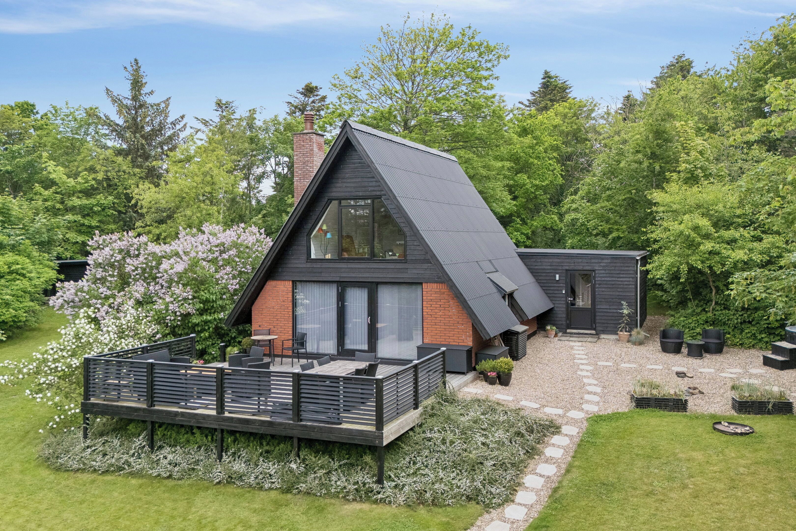 A modern house with a sloped roof, a deck, and a garden.
