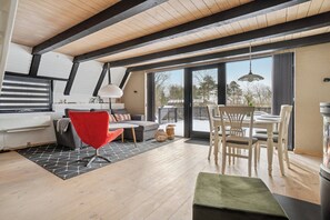 A modern living room with a sofa, red chair, dining table, and a fireplace. - Holiday home near beach and Limfjord (Thyholm)