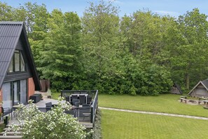 A modern house with a sloped roof, a patio with outdoor furniture, and a well-maintained lawn. - Holiday home near beach and Limfjord (Thyholm)