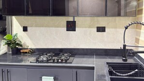 Een moderne keuken met zwarte kastjes, een gasfornuis, een spoelbak en een potplant.