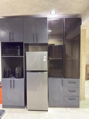 A compact kitchen with built-in appliances, including a refrigerator, microwave, and coffee maker, and a glass cabinet. - Rustic Limewash Haven, 3bd x3bath, Mojave, Lekki Phase 1 (Lekki)