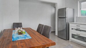 Una cocina moderna con refrigerador de acero inoxidable, armarios blancos y una mesa de comedor de madera con sillas.