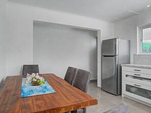A modern kitchen with a stainless steel refrigerator, white cabinetry, and a wooden dining table with chairs. - Panoramic 2BR: Ocean, Salt Pans with Flamingos & Infinity Pool (Cas Abao)