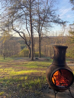 Ein großer Kochofen im Freien mit Feuer, umgeben von Bäumen und einer Wiese.
