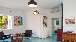 A room with a white cabinet, a wooden table, a black chair, and a bookshelf. - Green Oasis Elba- outdoor privacy & walk to the beach- privacy, greenery and the sea (Lacona)