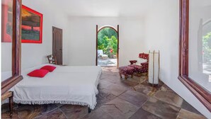 A bedroom with a bed, a chair, a table, and a view of the outdoors. - Green Oasis Elba- outdoor privacy & walk to the beach- privacy, greenery and the sea (Lacona)