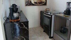 Une cuisine compacte équipée d’une machine à café, d’un four et d’un mixeur, le tout posé sur le plan de travail.