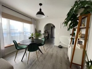 A dining area with a round table, green chairs, and a pendant light. - Eco-Friendly Bungalow in the Heart of West Seattle (Seattle)