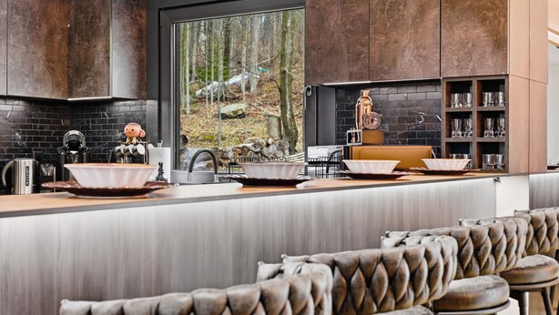 A modern kitchen with a large window, bar stools, and a built-in wine rack. - Sleeps 24! Luxury, Sauna, Hot tub, Zen room, Gameroom, pets (Tannersville)