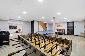 A room with a foosball table, a ping pong table, and a Netflix sign on the wall. - Spa-Style Luxury Lodge w/ Sauna, Hot Tub & Games (Tannersville)