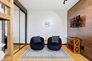 A modern room with two black bean bag chairs, a wooden console table, a Netflix poster, and a gaming mode sign on the wall. - Spa-Style Luxury Lodge w/ Sauna, Hot Tub & Games (Tannersville)