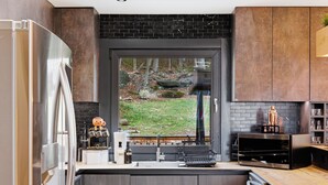 A modern kitchen with a large window, stainless steel appliances, and a black backsplash. - Sleeps 24! Luxury, Sauna, Hot tub, Zen room, Gameroom, pets (Tannersville)