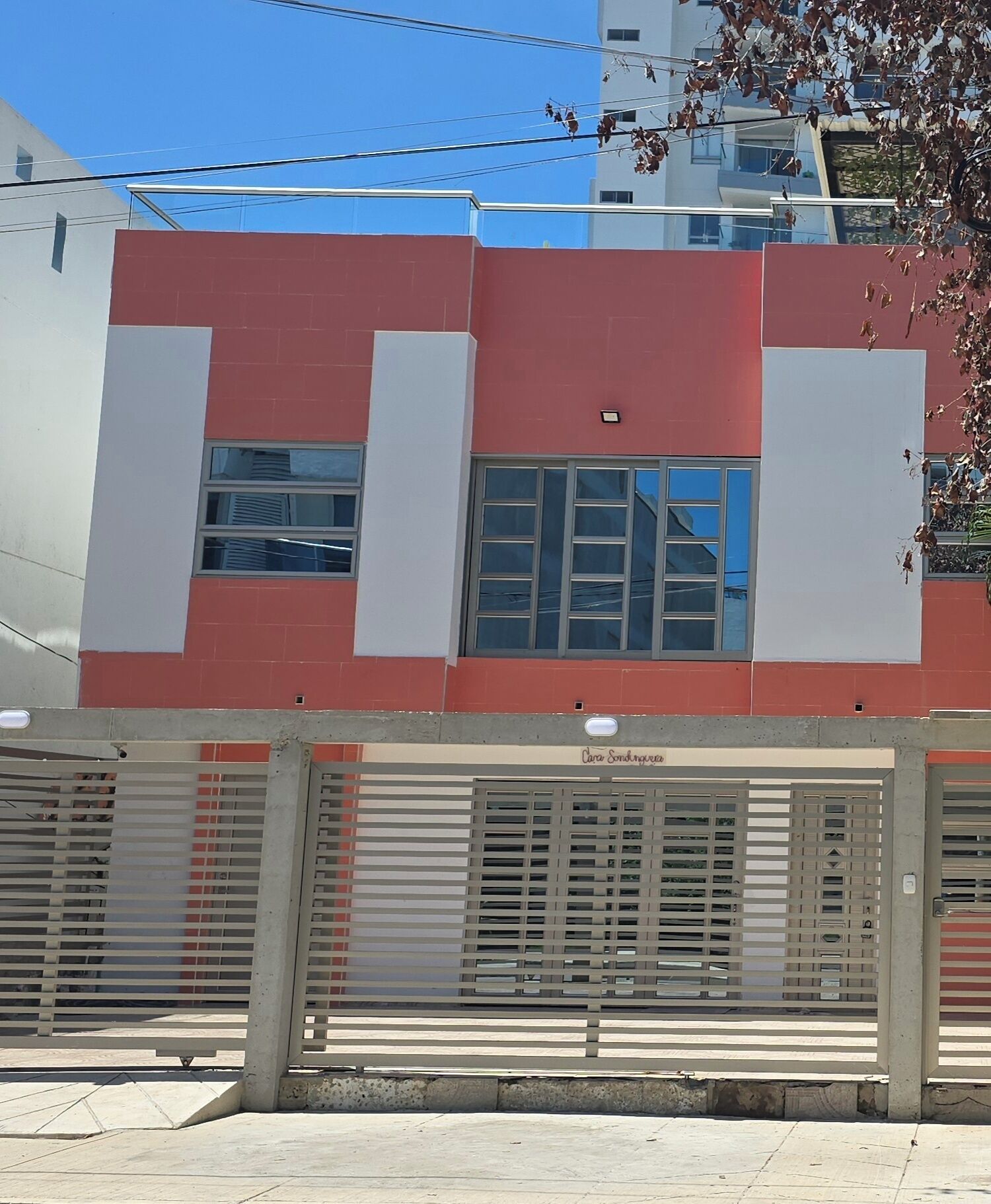 A building with a red and white facade, large windows, and a gated entrance.