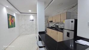 A modern kitchen with marble countertops, a refrigerator, and a stove. - Casa Sandunguera (Cartagena)