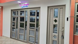 A building entrance with a glass door and a neon sign above. - Casa Sandunguera (Cartagena)