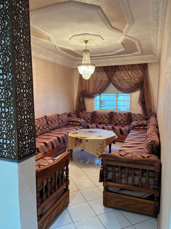 A room with a large, ornate sofa set, a wooden coffee table, and a chandelier.