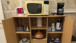 A kitchen with a microwave, coffee maker, and various kitchen utensils. - Premium Apartment | 5 Min from Rabat-Salé Airport | Free Parking & WiFi (Sale)