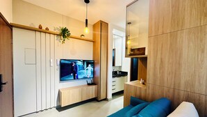 A modern living room with a TV, wooden cabinets, and a blue sofa. - Studio New Home | Practicality in one place. (Uberlândia)