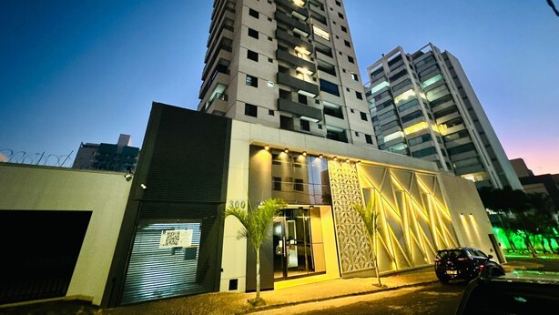 A modern building with a prominent entrance, large windows, and a parking area. - Studio New Home | Practicality in one place. (Uberlândia)