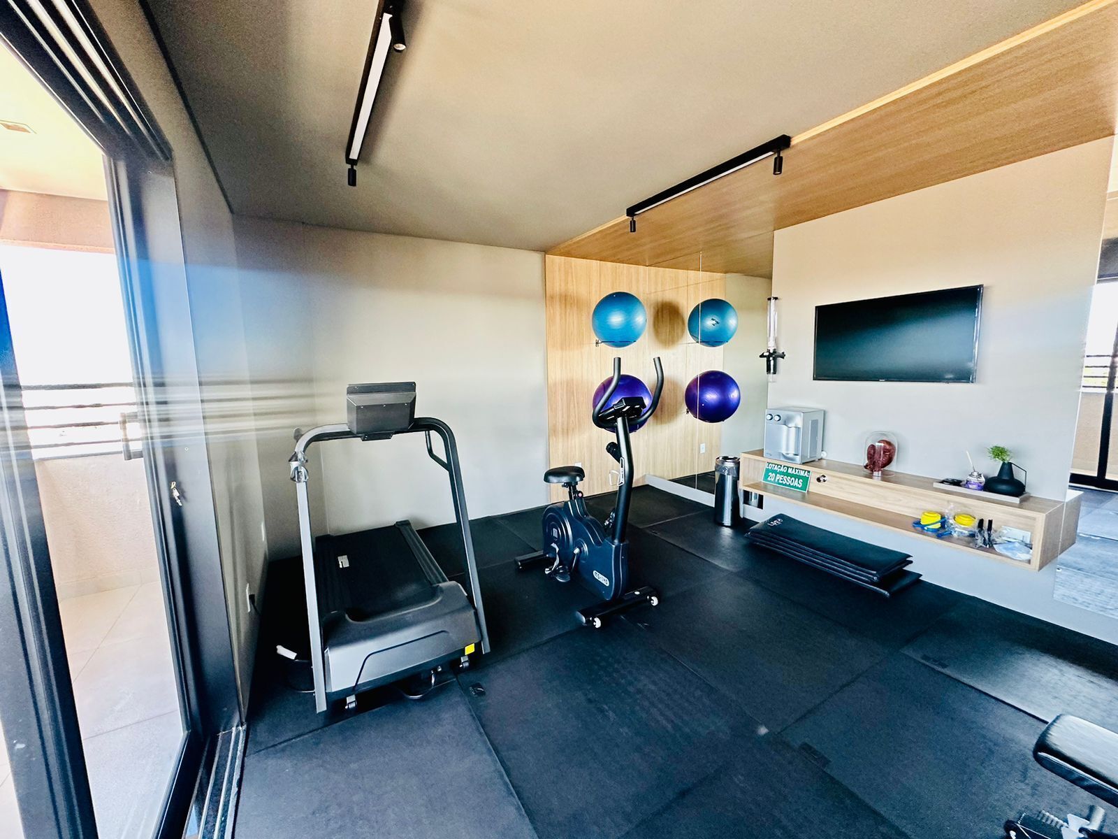 Een moderne sportschool met trainingsapparatuur, een televisie en een houten wand.