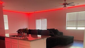 Une cuisine moderne dotée d’un îlot central, de meubles blancs et d’un ventilateur de plafond.