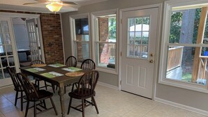 A dining area with a wooden table and chairs, a ceiling fan, and large windows with a view of the outdoors. - Available Masters! Only 2.2 miles from the course. (Augusta)
